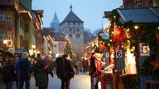 Fachwerkhäuser und Holzbuden, dahinter ein mittelalterlicher Turm - die Kulisse für den Weihnachtsmarkt in Rottweil.