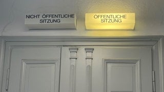 Geschlossene Eingangstüren vor dem Sitzungssaal im Landgericht Hechingen. Die Anzeige "Öffentliche Sitzung" leuchtet