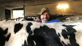 Landwirt Olaf Pank schaut über den Rücken von einer seiner Kühe.