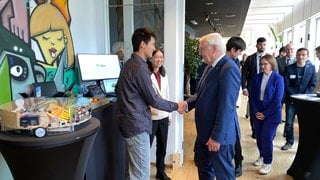 Der Bundespräsident Steinmeier schüttelt einem Schüler die Hand. Die Schüler dürfen ihm ihre selbst entwickelten KI-Projekte in Tübingen vorstellen.