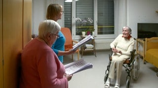 Zwei Ehrenamtliche singen im Zimmer einer Bewohnerin des Seniorenzentrums am Markwasen in Reutlingen. Das Singen am Pflegebett ist ein besonderes Ehrenamt. 