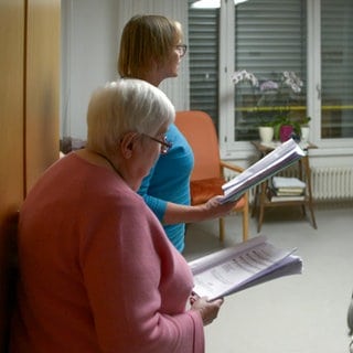 Zwei Ehrenamtliche singen im Zimmer einer Bewohnerin des Seniorenzentrums am Markwasen in Reutlingen. Das Singen am Pflegebett ist ein besonderes Ehrenamt. 