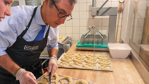 Cem Özdemir, Grüne, Bundesminister für Ernährung und Landwirtschaft, backt Brezeln in der Bäckerei Beckabeck in Bad Urach.