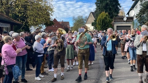 Beim Almabtrieb der Feuerwehrziege in Alpirsbach-Peterzell läuft die Musikkapelle im Festumzug mit, viel Publikum drängt sich am Straßenrand.