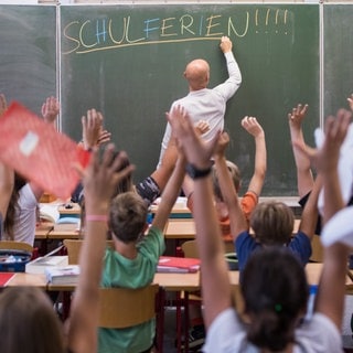 Lehrerschreibt an die Tafel Schulferien