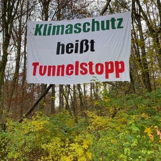 Ein Banner mit dem Schriftzug "Klimaschutz heißt Tunnelstopp" in einem Wald bei Tübingen. Aktivisten haben es aus Protest gegen den Schindhaubasistunnel angebracht. Der geplante Tunnel soll die B27 entlasten.