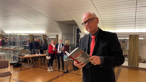 Ralf Bernd Herden hält im Stadthaus Freundenstadt sein neues Buch in der Hand. Er hat sich mit der Biografie von Helmut Weihenmaier beschäftigt.