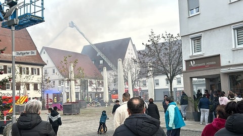 Von einer langen Drehleiter aus spritzt die Feuerwehr Wasser auf die brennenden Häuser in der Metzinger Innenstadt im Kreis Reutlingen.