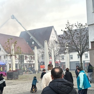 Von einer langen Drehleiter aus spritzt die Feuerwehr Wasser auf die brennenden Häuser in der Metzinger Innenstadt im Kreis Reutlingen.