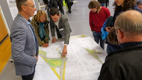 Besucherinnen und Besucher der Infoveranstaltung sprechen mit Experten des Regierungspräsidiums Tübingen über die aktuellen Pläne und den Verlauf der B27-Umfahrung mit dem Schindhaubasistunnel.