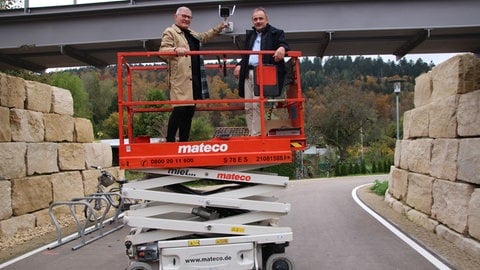 Tuttlingens Oberbürgermeister Michael Beck montiert gemeinsam mit einem Mitarbeiter einer Multimediafirma eine Kamera am Durchbruch vom Bahnhof zur Donau