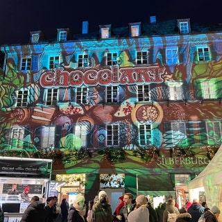 Im Rahmen der chocolART wird bei einer Lichtershow ein buntes Kunstwerk auf ein Haus am Tübinger Marktplatz projiziert. 