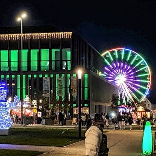 Nächtlich beleuchteter Weihnachtsmarkt mit Riesenrad um die Stadthalle in Reutlingen. Die Betreiber kämpfen mit stark erhöhten GEMA-Gebühren.