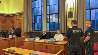 Der Angeklagte sitzt neben seinem Anwalt im Gerichtssaal des Tübinger Landgerichts. Er soll seine Ehefrau in Bad Liebenzell getötet haben, und dann mit ihrer Leiche auf der Rückbank einen Unfall auf der A81 gebaut haben.