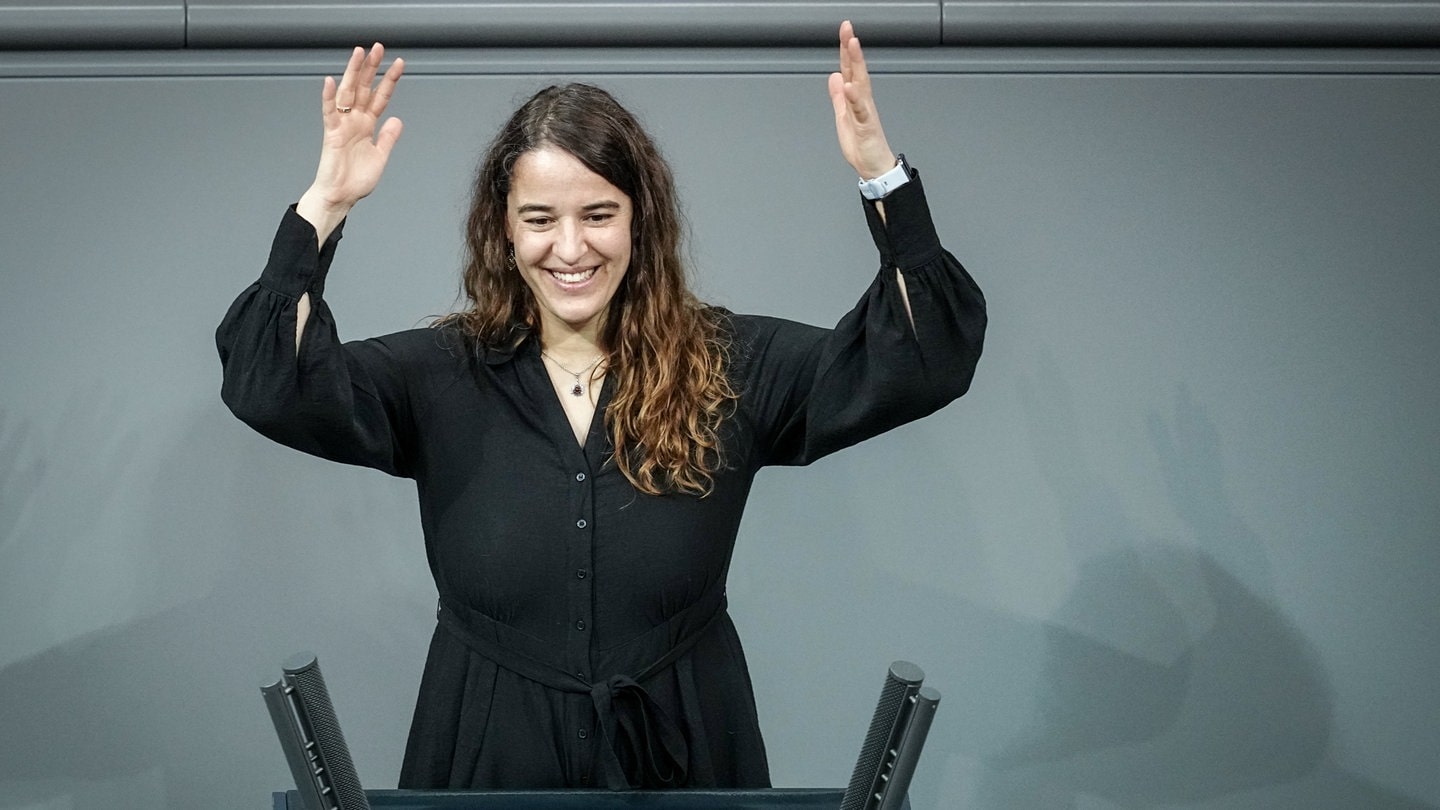 Heike Heubach (SPD), die erste gehörlose Bundestagsabgeordnete, steht vor Beginn der Sitzung des Bundestags für ein Foto am Rednerpult. Dieses Zeichen steht für Applaus in der Gebärdensprache.