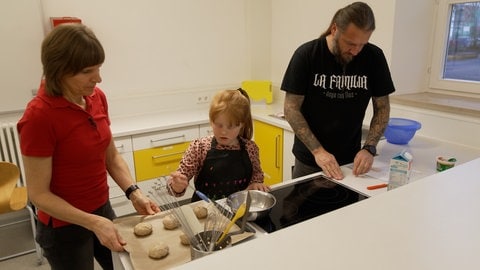 Ernährungsberaterin und Kursleiterin Elvira Kalbacher bereitet mit der siebenjährigen Malou und ihrem Vater Jörg Vollkornbrötchen zu.