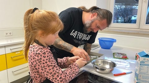 Die siebenjährige Malou und ihr Vater Jörg bereiten zusammen Vollkornbrötchen bei dem Kurs für gesunde Ernährung zu.