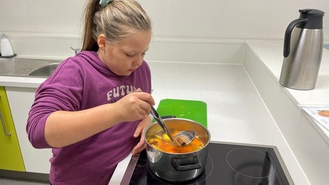 Die neunjährige Kursteilnehmerin Emily rührt in dem Topf mit selbstgemachtem zuckerfreiem Kinderpunsch.