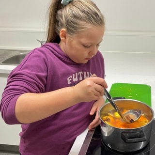 Die neunjährige Kursteilnehmerin Emily rührt in dem Topf mit selbstgemachtem zuckerfreiem Kinderpunsch.