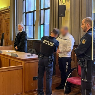 Ein Mann steht als Angeklagter im Landgericht Tübingen neben einem Justizbeamten. Er wurde verurteilt, seine Ehefrau in Bad Liebenzell getötet zu haben. 