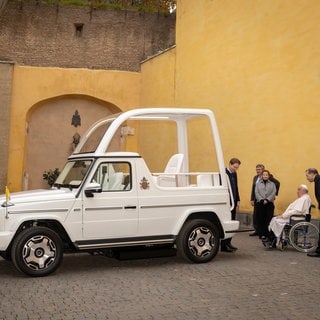 Papst Franziskus sitzt im Rollstuhl vor dem neuen Papamobil im Vatikan - der Spezialhersteller Paravan aus Aichelau hat es barrierefrei aufgerüstet.