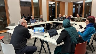 Zehn Menschen sitzen an einem Konferenztisch im Landratsamt Tübingen. Sie arbeiten für ein Magazin und besprechen, wie sie über das Thema "Rückkehr nach Syrien" berichten werden.