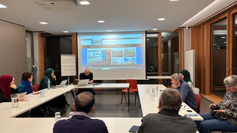 Zehn Menschen sitzen an einem Konferenztisch im Landratsamt Tübingen. Sie arbeiten für ein Magazin und haben eine Besprechung.