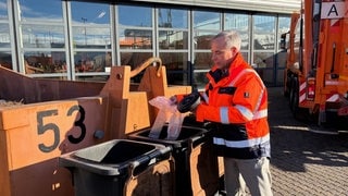 Der Chef der technischen Betriebsdienste Reutlingen zieht eine Plastiktüte aus einer Biomülltonne. Solche falschen Stoffe soll es im Biomüll dank Kameras und künstlicher Intelligenz bald nicht mehr geben.