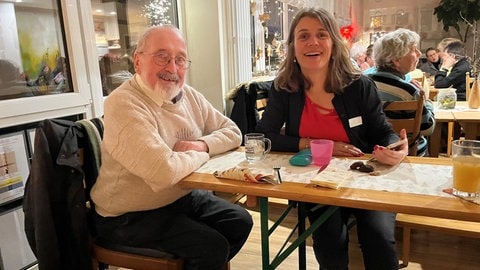 Ein Gast und ein Mitglied des Organisationsteams von "Weihnachten nicht alleine" sitzen fröhlich an einem Tisch im Familienzentrum Freudenstadt.