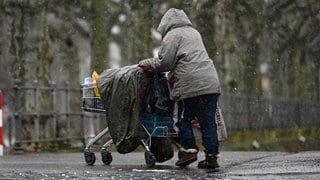 Obdachlose Frau mit Einkaufswagen im Winter