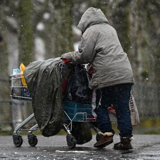 Obdachlose Frau mit Einkaufswagen im Winter