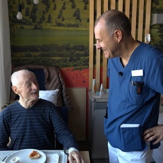 Ein Patient in einem Krankenzimmer bekommt von Arzt Volker Damm aufmunternde Worte