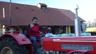 Landwirt Olaf Pank sitzt auf seinem roten Traktor und winkt zum Abschied