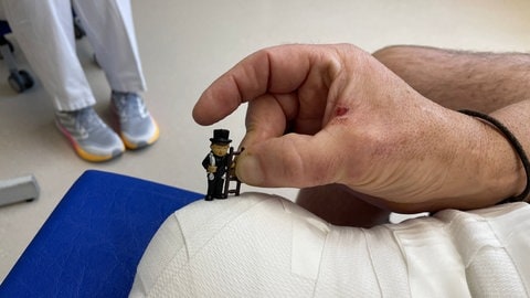 Eine Hand hält eine kleine Schornsteinfeger-Figur