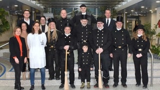 Gruppenbild von Schornsteinfegern und Schornsteinfegerinnen, die Patienten in der BG Klinik besuchen und Glück verteilen.