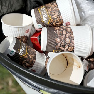 Kaffeebecher und andere Einwegverpackungen liegen in einem Mülleimer.