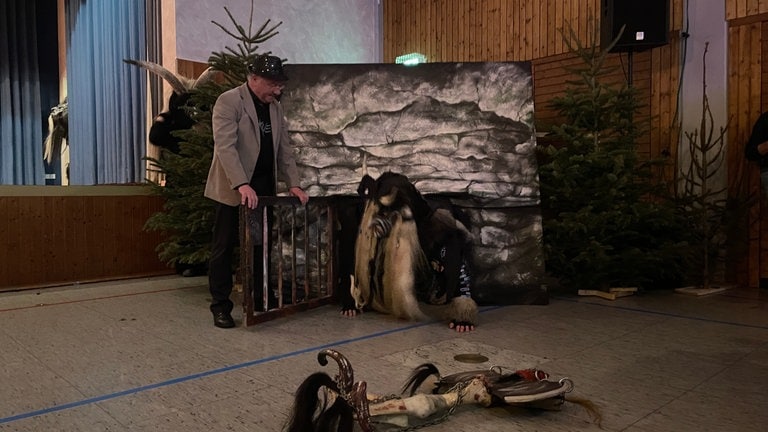 Ein Teufel mit Häs und Maske von der Narrenzunft Talheim 2010 "Seibachdeifel" e.V. aus Mössingen wird aus der Höhle gelassen und kriecht heraus. Mit dem Häsabstauben hat die Fastnacht an Dreikönig begonnen.