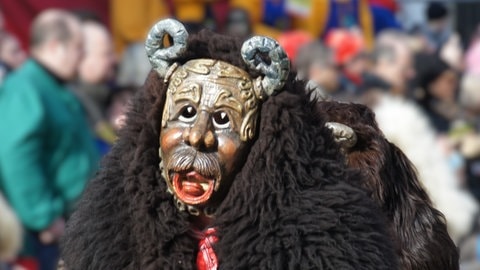 Das Pompele der Narrenzunft Rottenburg trägt ein dunkelbraunes Lammfell ala Haube und eine Maske mit Hörnern.