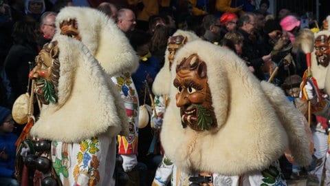 Ein verkleideter Mann feiert im traditionellen Ahland-Häs auf der Straße in Rottenburg die Fasnet