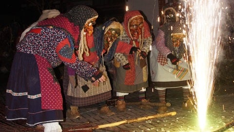 Vier verkleidete Menschen im Hexenkostüm vor einem brennenden Feuer beim traditionellen "Äscha-Deida" in Bühl.