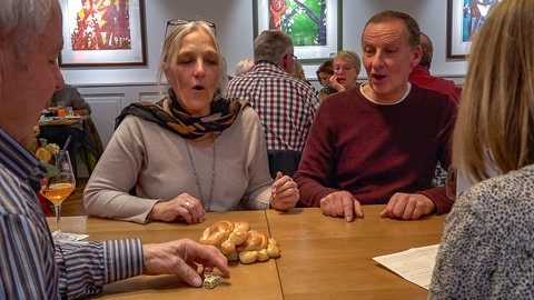 Mehrere Personen an einem Tisch beim Würfelspiel "Mutscheln" in Reutlingen. Die Mutschel ist ein traditionelles Hefegebäck, um das beim "Mutscheln" gewürfelt wird.