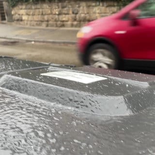 Glatteis in Tübingen: Der Deckel einer Mülltonne ist vereist, im Hintergrund fährt ein Auto vorbei. 