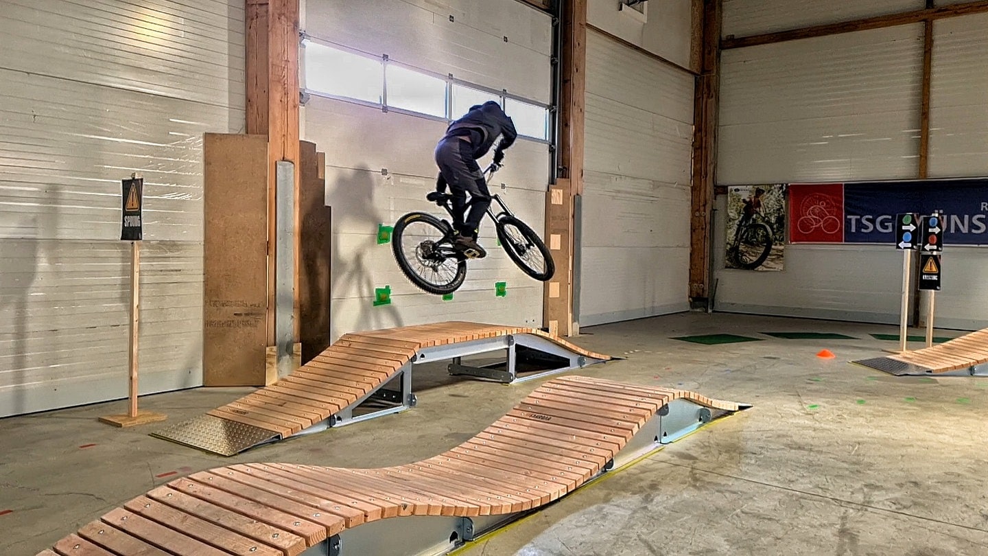 Ein Jugendlicher springt in Münsingen in einem neuen Indoor-Bike-Park über ein Hindernis mit dem Mountainbike.