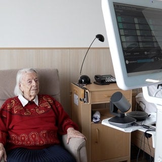 Die Patientin sitzt auf einem Sessel in ihrem Zimmer im Pflegeheim. Vor ihr steht der Medienturm, mit dem sie von der Ärztin telemedizinisch untersucht wird. Das Pilotprojekt HeimDoc ist ein Versuch der Reutlinger Kreiskliniken und der RAH, die hausärztliche Versorgung zu verbessern.