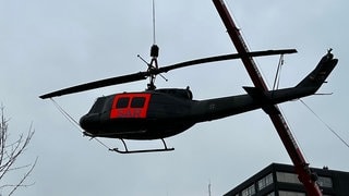 der alte Hubschrauber wird mit einem Kran auf seinen Sockel gehoben