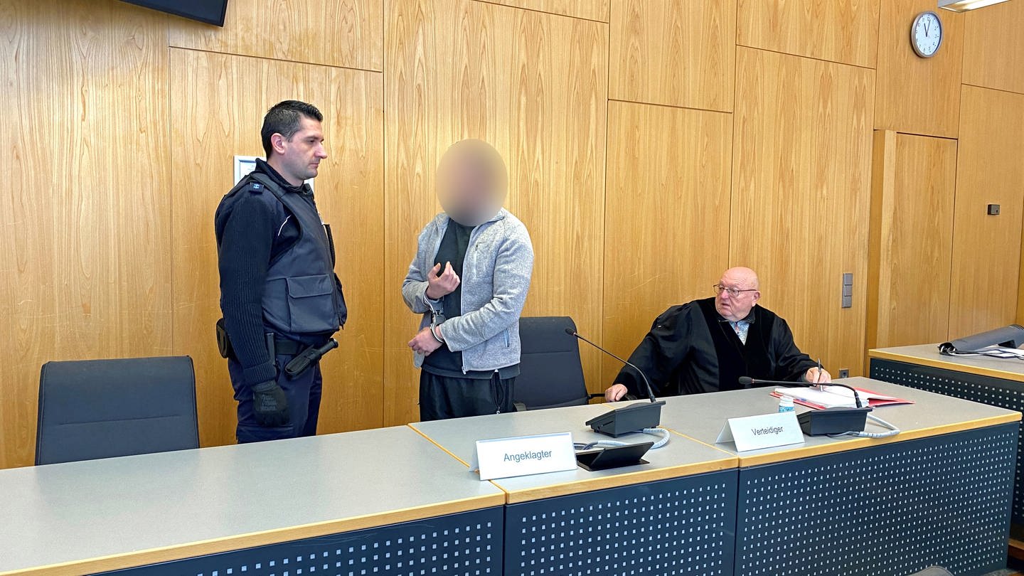 Angeklagter, Justizbeamter und Anwalt in einem Saal des Landgerichts Ulm. Das Landgericht Ulm hat am Dienstag einen 47-Jährigen wegen eines Brandanschlags auf die Synagoge in Ulm zu zwei Jahren und neun Monaten Gefängnis verurteilt.
