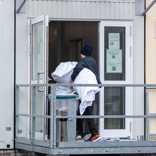 Ein Mann bringt Bettwäsche in einen Container. In Blaustein Herrlingen sollen in einer solchen Unterkunft 100 bis 200 Geflüchtete Platz finden. (Symbolbild)