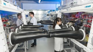 Aufbauten in einem Labor mit Forscherinnen und Forscherin. Im Helmholtz-Institut in Ulm wird nach Alternativen für Lithium-Ionen-Batterien gesucht. 