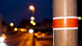 Banderolen statt Strom: Die Stadt schaltet Straßenlaternen ab, um Energie zu sparen. Welche es sind, verrät die rot-weiße Banderole.