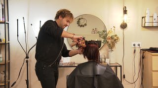 Friseurmeister Christoph Sponer schneidet einer Kundin die Haare. Er ist seit seiner Geburt gehörlos. Davon hat er sich aber nicht abhalten lassen, sich seinen Traum vom eigenen Friseursalon in Aalen zu erfüllen. 